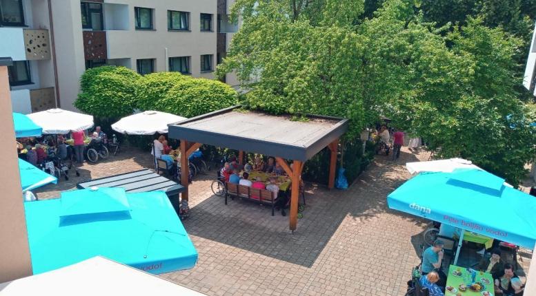 Pogled na atrij kjer pod senčniki sedijo stanovalci