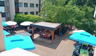 Pogled na atrij kjer pod senčniki sedijo stanovalci